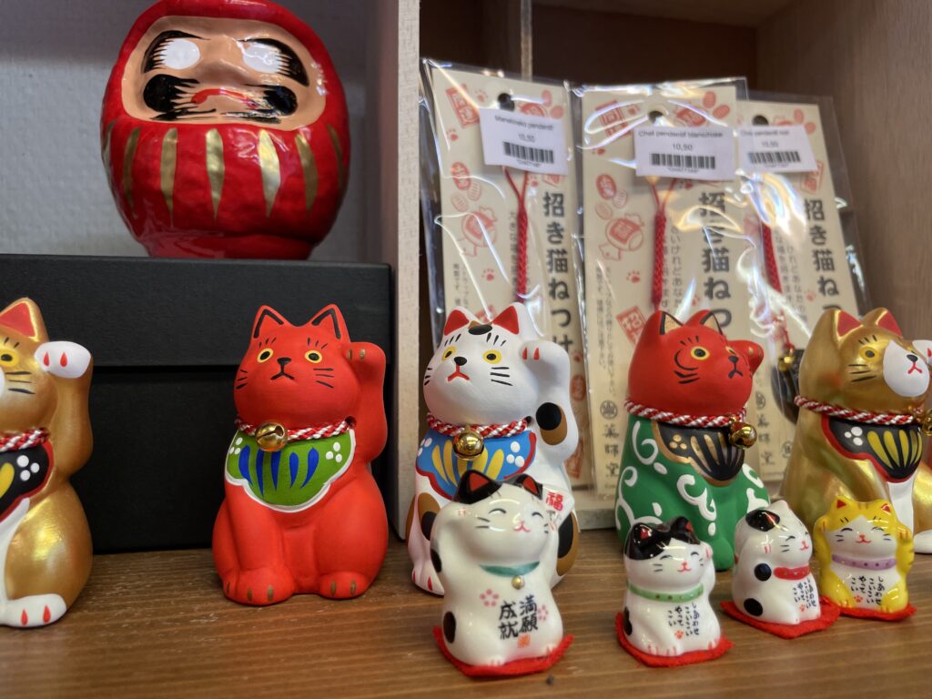 Figurines porte-bonheur japonaises : maneki-neko multicolores et statuette daruma rouge