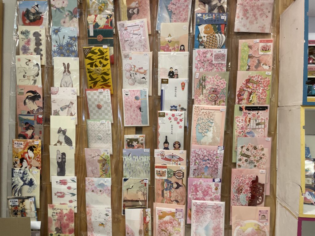 Mur décoré de cartes postales artistiques et papiers japonais dans la boutique Le Temps Cerise